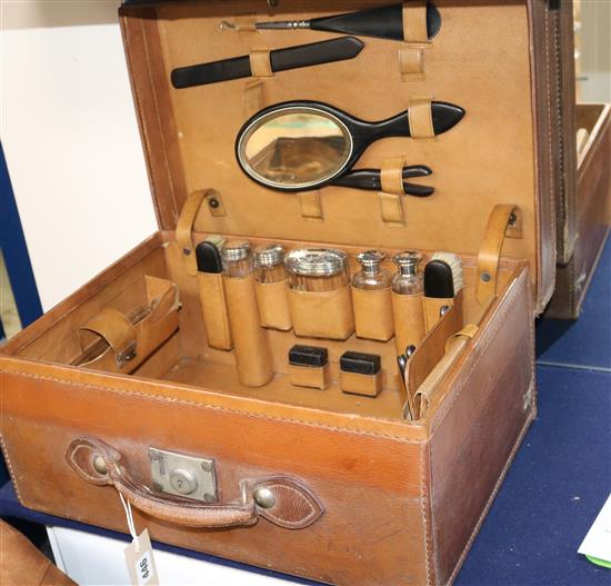 A late Victorian leather travelling toilet case containing silver topped bottles etc.